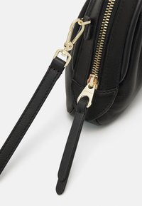 Black leather handbag with a textured finish, gold zipper, and hardware. Features a detachable strap for versatility and practicality.