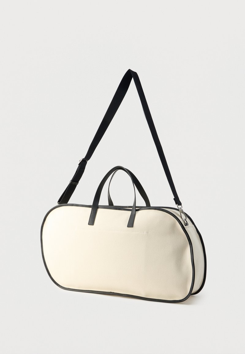 Canvas-Tasche in Creme mit schwarzen Lederakzenten; ovale Form, zwei Griffe und ein verstellbarer Schulterriemen. Verfügt über einen Reißverschluss.