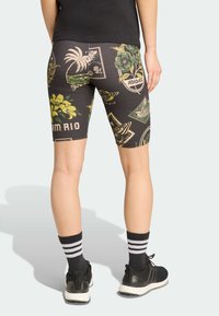 Calções de ciclismo pretos com estampados tropicais e designs florais. Apresentam uma cintura elástica e um corte ajustado. Acompanhados por meias listadas em preto e branco.