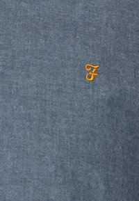 Katoenen t-shirt in donkerblauw met fijne textuur, voorzien van een klein, geborduurd oranje "F" logo aan de linkerkant.