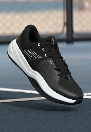 Baskets de sport noires avec une tige texturée, des accents blancs et une semelle blanche rembourrée. Elles présentent des lacets et un design perforé pour une meilleure respirabilité.