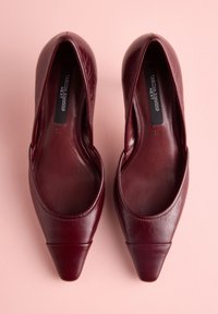 Bordové kožené lodičky s hladkou textúrou, špicatou špičkou a bočnými výrezmi. Majú mierne zvýšený podpätok a minimálne prešívanie.