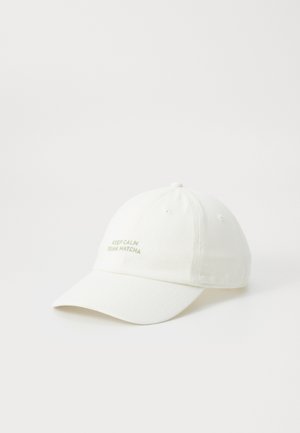 Gorra blanca de algodón con visera curva, con texto verde bordado que dice "MANTÉN LA CALMA Y BEBE MATCHA." Diseño clásico de seis paneles.