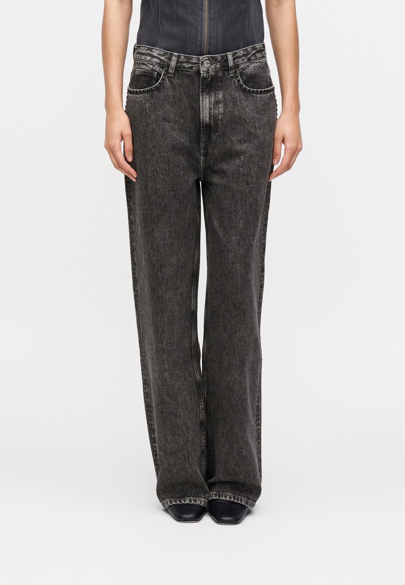 Μαύρο τζιν παντελόνι με φαρδύ πόδι, ξεθωριασμένο σχέδιο, πέντε τσέπες και αντίθετη ραφή, με ψηλή μέση και άνετη εφαρμογή.