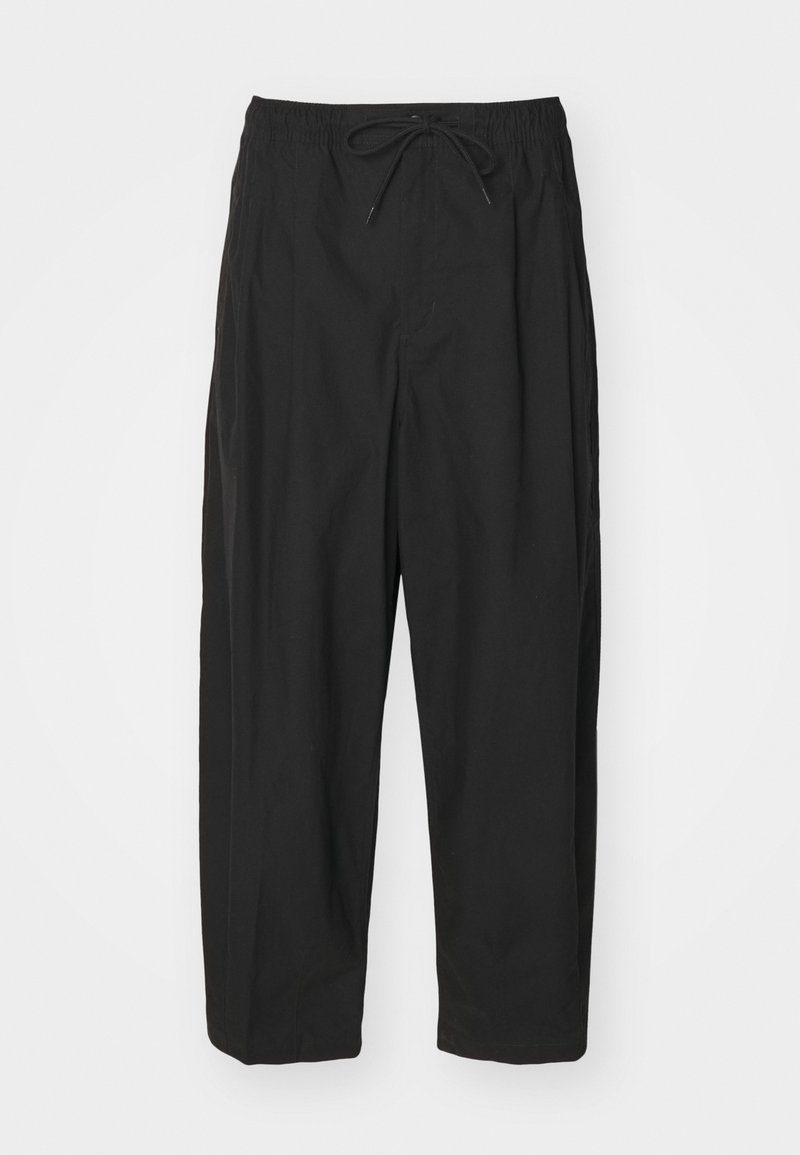 Pantaloni neri con cintura elastica, chiusura con cordino e vestibilità ampia. Realizzati in un tessuto morbido, presentano un design minimalista.