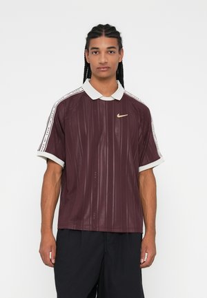 Burgundská polo košile s vertikálním žebrováním, bílým límečkem a pruhy na ramenou s černým brandingem "Nike". Zlatý akcent loga.