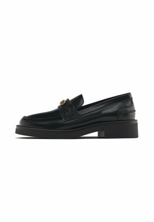 Mocassin en cuir noir avec un petit talon carré et une petite boucle décorative dorée sur le dessus, vu de profil.