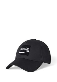 Gorra de béisbol negra hecha de tela, con un parche cuadrado blanco del logo de Coca-Cola en el frente y un visera curva. Detalles de superficie texturizada.