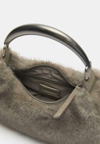 Kunstfell-Handtasche in gedämpftem Grau mit rundem Metallgriff. Das Innere verfügt über eine Reißverschlusstasche und einen Stofffutter. Reißverschluss-Detail sichtbar.