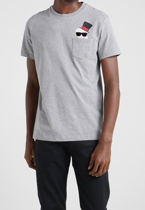 T-shirt en coton gris à manches courtes, avec un graphique représentant un personnage portant un haut-de-forme et des lunettes de soleil sur la poche gauche de la poitrine.