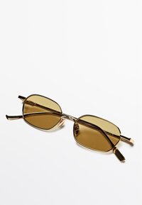 Occhiali da sole rettangolari con lenti marroni, montatura in metallo dorato, aste sottili e hardware della cerniera ben visibile. Design leggero e minimalista.