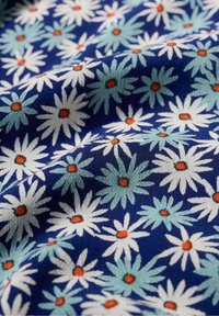 Tissu bleu à motif floral présentant des marguerites blanches et des pétales bleu clair, accentués de centres orange, avec une finition texturée.
