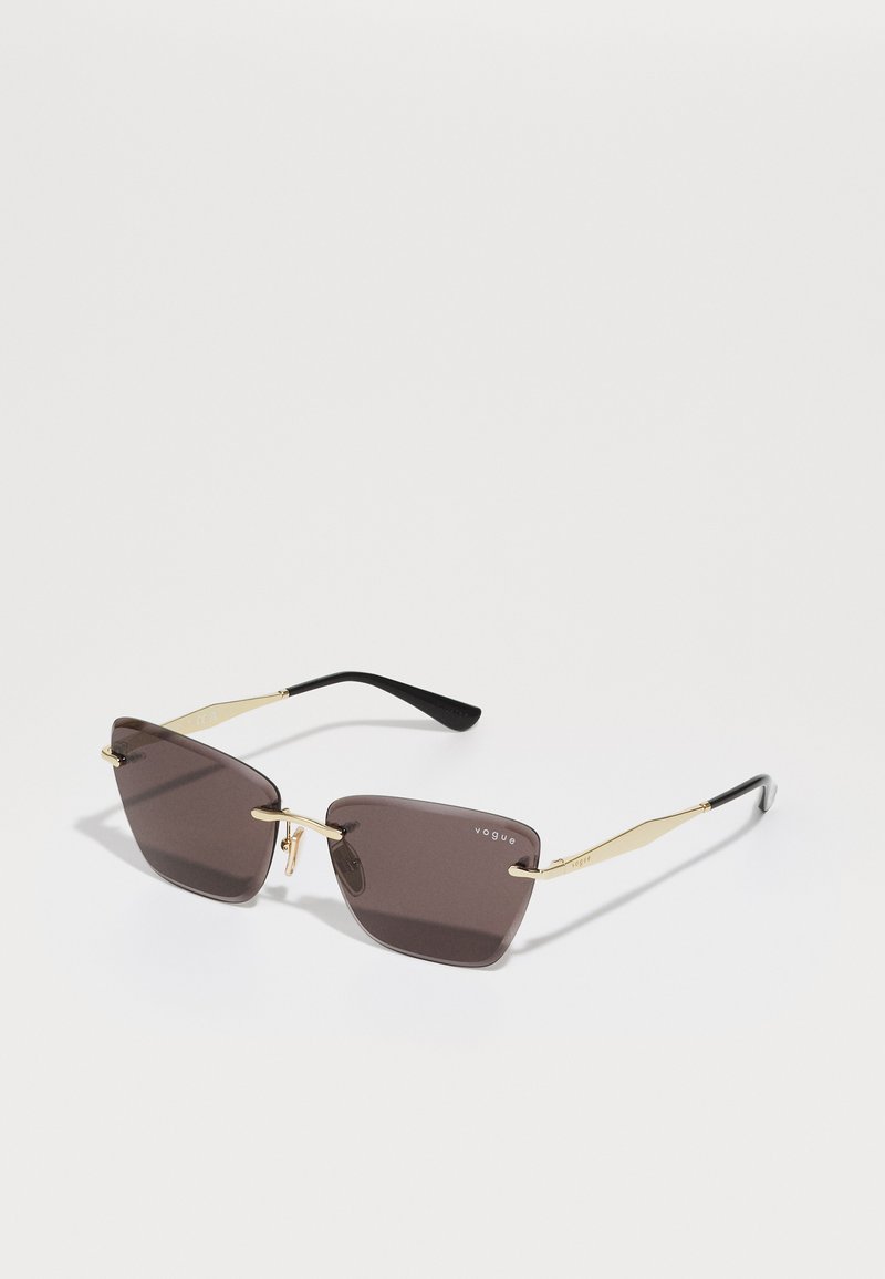 Óculos de sol quadrados com tonalidade castanha e acabamentos em metal dourado, apresentando hastes finas e angulares e uma forma distinta. Logotipo gravado na lente.