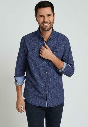 Chemise bleu marine à boutons avec un motif floral, poignets contrastants bleu clair et col classique, fabriquée à partir d'un tissu lisse.