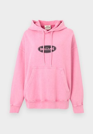 Ružičasti pulover s kapuljačom od mekane pamuka s prednjim džepom u obliku klokana. Ima crni ovalni logotip na prsima i kapuljaču s vezicama.