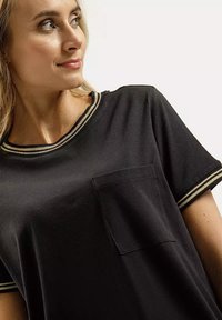 Czarny T-shirt z krótkimi rękawami, z jasnymi paskami na dekolcie i krawędziach rękawów, z kieszenią na piersi. Gładka struktura materiału.