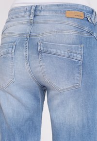 Jeans de mezclilla azul claro con un acabado deslavado. Cuenta con dos bolsillos traseros con detalles de costura y un parche de cuero de la marca en la cintura.