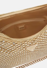 Borsa a pochette dorata con un esterno testurizzato decorato con borchie argentate, dotata di chiusura con zip e di una tasca interna con etichetta del logo.