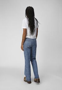 High-waisted blue jeans with a straight leg, medium denim wash, and two back pockets, paired with a white short-sleeve t-shirt.