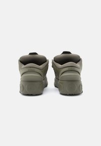 Ελιάς πράσινα αθλητικά παπούτσια με υφή στο άνω μέρος, στρογγυλή μύτη και επενδεδυμένη φτέρνα. Διαθέτουν λαβή στην πίσω πλευρά και εξωτερική σόλα με υφή για καλύτερη πρόσφυση.