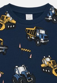 T-shirt in cotone blu navy con un'illustrazione di veicoli da costruzione, tra cui camion e trattori, intervallati da coni stradali e barriere.