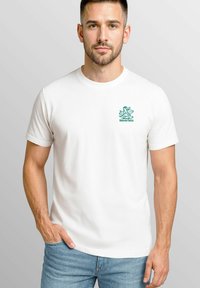 White cotton t-shirt featuring a green logo on the left chest, short sleeves, a crew neck, and a relaxed fit.