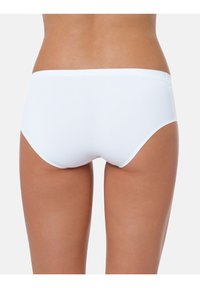 Costumi da bagno bianchi con una texture liscia e leggermente lucida. Taglio a vita bassa e bordi senza cuciture per una vestibilità ottimale. Design minimalista.