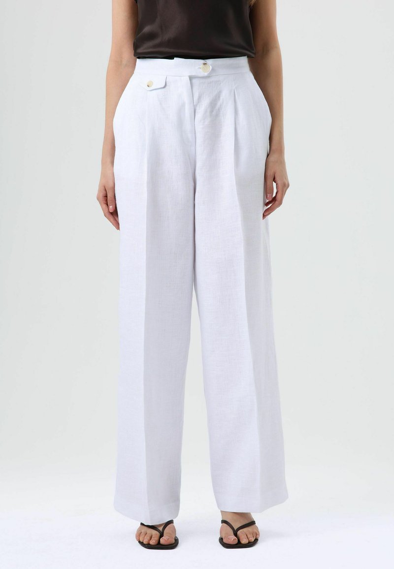 Wide-leg white linen trousers with pleats, featuring a high waist and two decorative buttons. Soft texture and lightweight appearance.