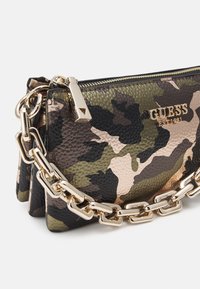 Camo-gepatroneerde clutch tas in gestructureerd leer met een gouden kettingriem, voorzien van het merklogo en een metalen ritssluiting.