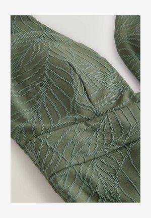 Strukturiertes grünes Gewebe mit einem Blattmuster in hellblauer Stickerei, das eine weiche Textur und eine glatte Oberfläche aufweist.