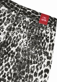 Musta-valkoiset leopardi-printtiiset farkkushortsit, joissa on koristeena paljetit ja punainen "OH APRIL" -etiketti housujen vyötäröllä.