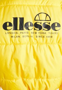 Veste jaune vif avec logo noir ellesse et noms des grandes villes ainsi que "Depuis 1959" imprimés au dos.