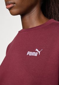 Bordeaux crewneck sweatshirts lavet af blødt stof, med et hvidt broderet Puma-logo på brystet. Glat tekstur og tætsiddende design.