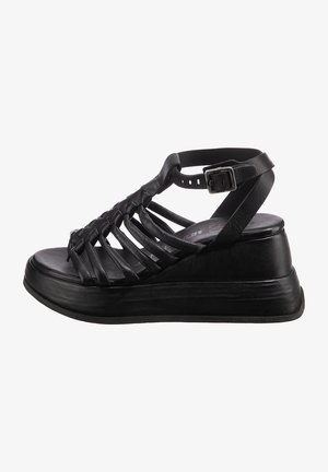 Sandalia cuña de cuero negro con múltiples correas entrelazadas, plataforma acolchada y correa de tobillo ajustable con hebilla de metal.