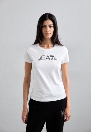 Biela krátka rukávová tričko s čiernym logom "EA7" a pruhmi. Mäkko bavlnené tkanivo, priliehavý strih, skombinované s čiernymi nohavicami.