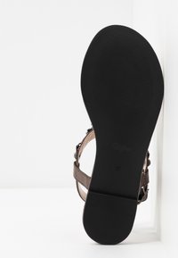 Brown sandal with a textured footbed, flat black rubber sole, and adjustable strap. Size 37 is displayed on the sole.