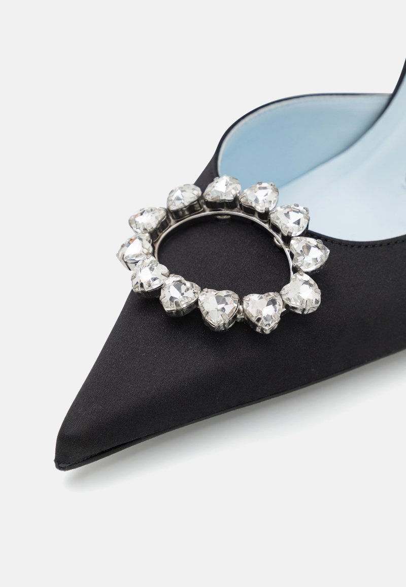 Chaussure noire en satin à bout pointu avec un intérieur bleu clair, dotée d'un accent circulaire métallique orné de rhinestones transparents en forme de cœur.