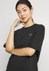 T-shirt di cotone nera con scollatura rotonda, vestibilità comoda e maniche corte. Presenta un piccolo logo bianco sul lato sinistro del petto.