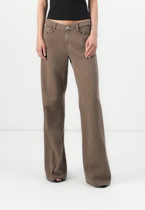 Hellbraune weite Jeans mit hoher Taille, seitlichen Taschen und Reißverschluss. Der Stoff wirkt glatt mit minimaler Textur.