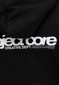 Felpa nera con cappuccio realizzata in morbido tessuto, caratterizzata da una grande scritta bianca che recita "project core CREATIVE DEPT." con ulteriore testo sottostante.