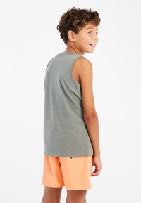 Grijze mouwloze tanktop met een ronde hals, gecombineerd met lichtoranje shorts. Zachte stof, casual pasvorm, geen zichtbare patronen of logo's.