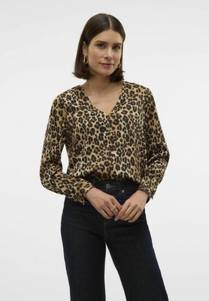 Halenka s leopardím potiskem a výstřihem do V, s dlouhými rukávy, vyrobená z hladkého materiálu. Vytvořeno s tmavými džínami a minimálním příslušenstvím.