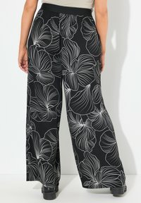 Zwarte wijdcelan broek met witte bloemenlijnpatronen, elastische tailleband en een gladde textuur. Geschikt voor casual of semi-formele gelegenheid.