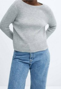 Grauer gerippter Pullover mit weitem Ausschnitt, langen Ärmeln und lockerer Passform, kombiniert mit hellblauen, geraden Jeans.