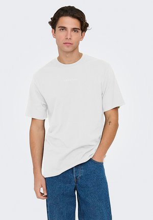 White short-sleeve t-shirt made of cotton with a round neckline and a small "ONLY & SONS" logo printed in the center. Worn with blue jeans.