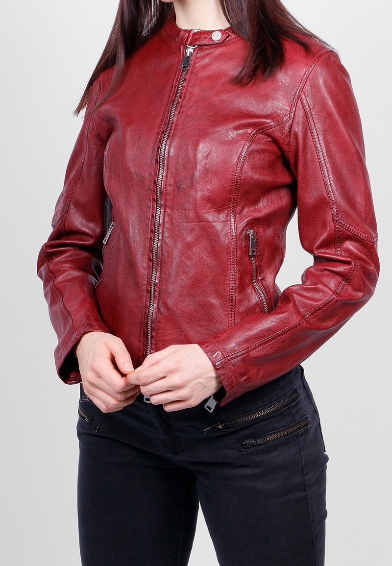 Chaqueta de cuero rojo con un diseño ajustado, cierre de cremallera y bolsillos laterales. Presenta una textura suave y detalles de costura mínimos.