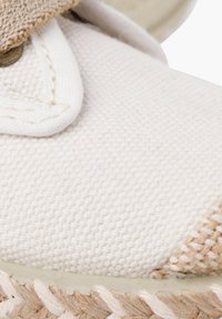 Baskets en toile de coton crème avec un accent en beige tissé, dotées d'une semelle en caoutchouc et d'un bord en corde de jute. Œillets en métal pour les lacets.