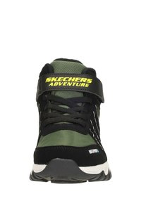 Sneakers Skechers Adventure z czarną i oliwkową siateczką, z zapięciem na sznurówki, paskiem na rzep i białą gumową podeszwą o teksturowanym chwycie.