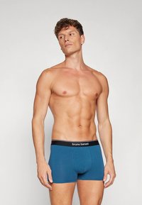 Modro bombažne bokser hlačke s črnim pasom, na katerem je napis "bruno banani". Gladek tekstura in prilegajoč dizajn. Model je brez majice.