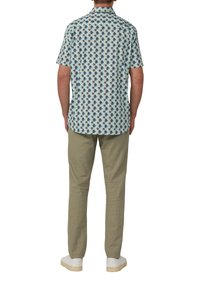 Korte mouwen shirt in lichtblauw met een palmbomenpatroon. Gepaarde met lichte khaki broek en witte sneakers. Casual pasvorm en eenvoudig ontwerp.